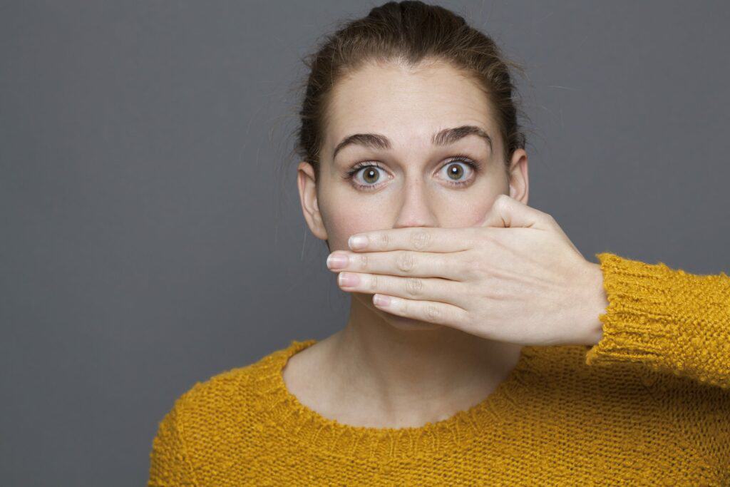 Gum disease causes woman to cover her mouth with her hand.