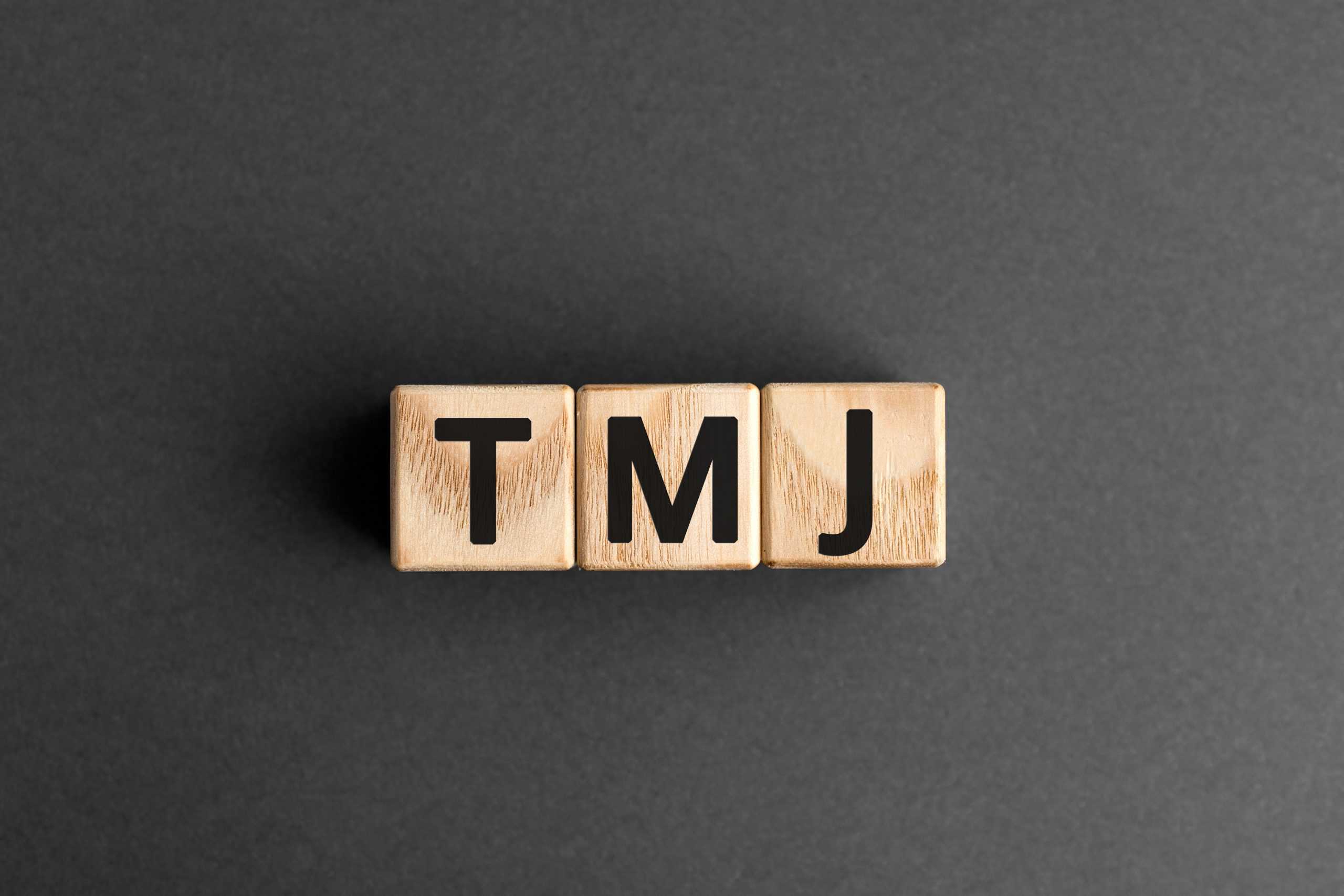 TMJ treatment: TMJ letters on wood blocks over black background