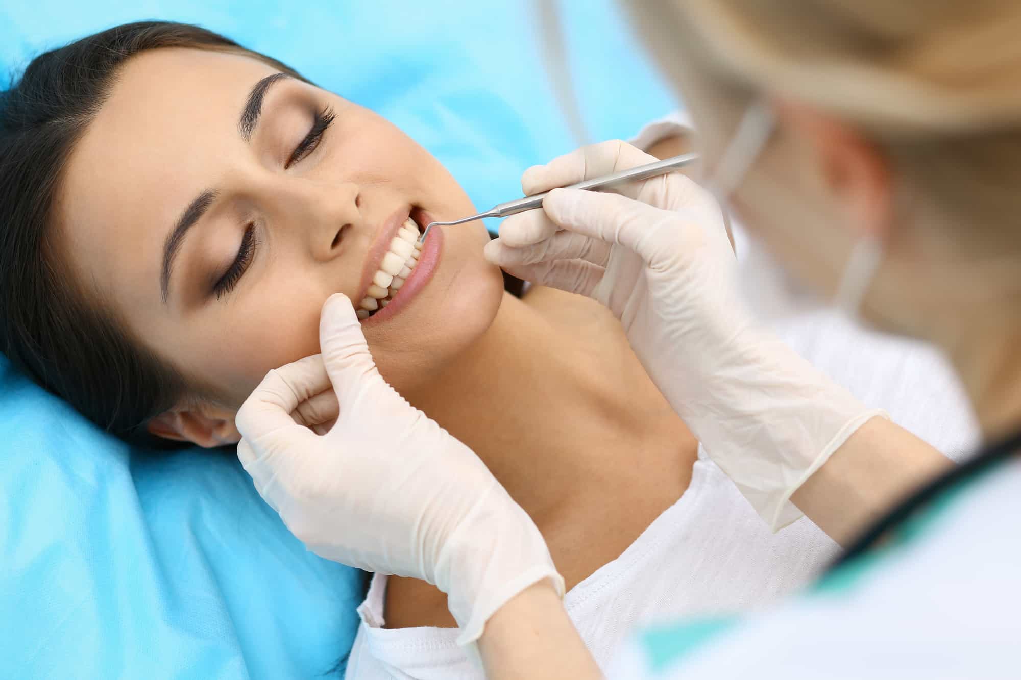 Woman getting teeth flossed by dentist