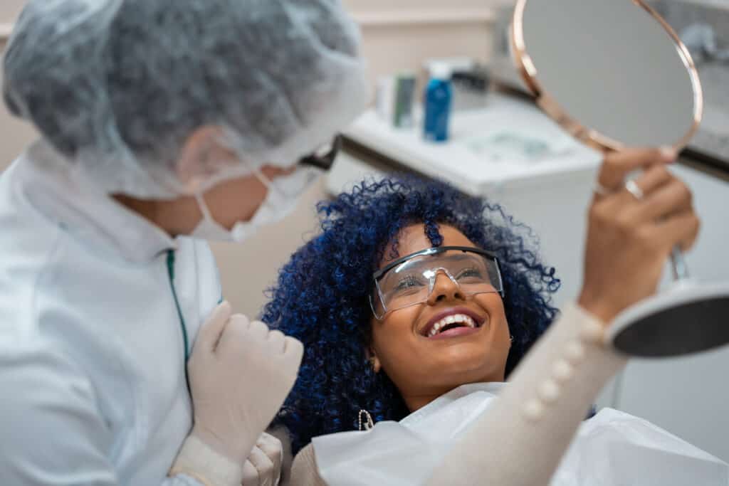 Cosmetic dentistry: Woman patient looking at teeth in mirror in dental chair