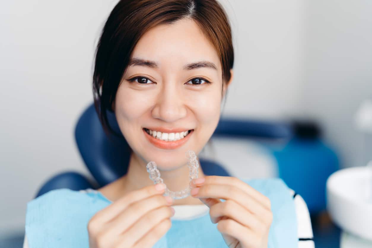Woman holding invisible braces aligners - Invisalign