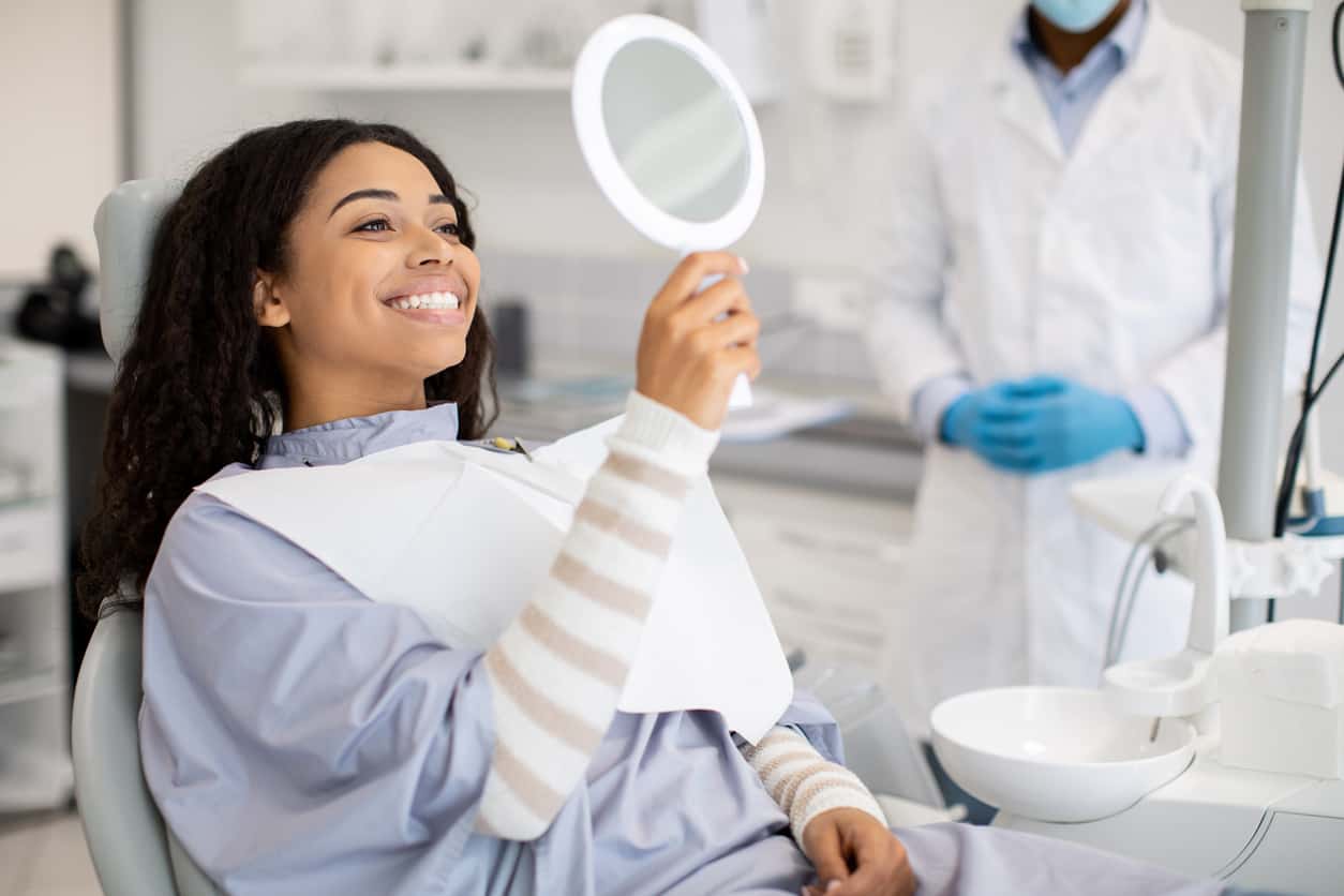 Woman at the dentist office smiling at a mirror